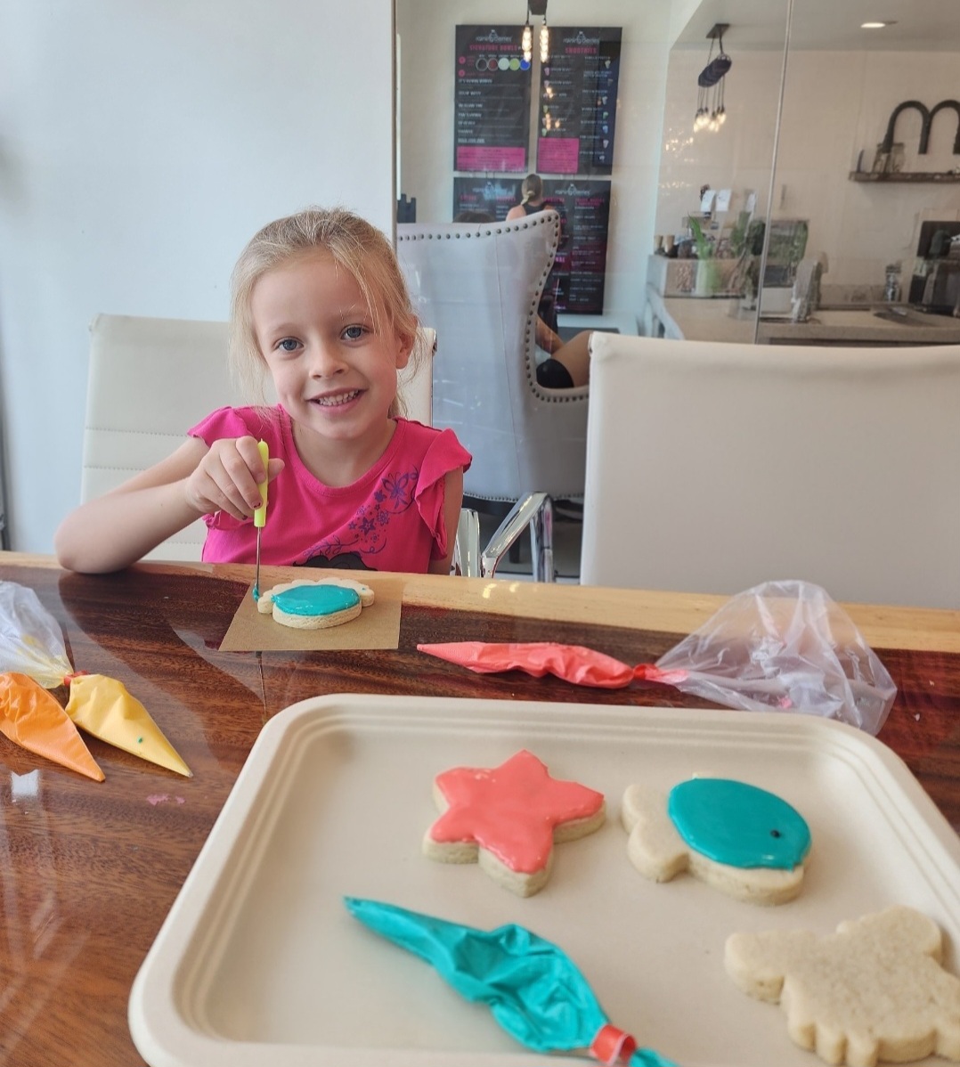 Young girl smiling while decorating a sugar cookie at a class