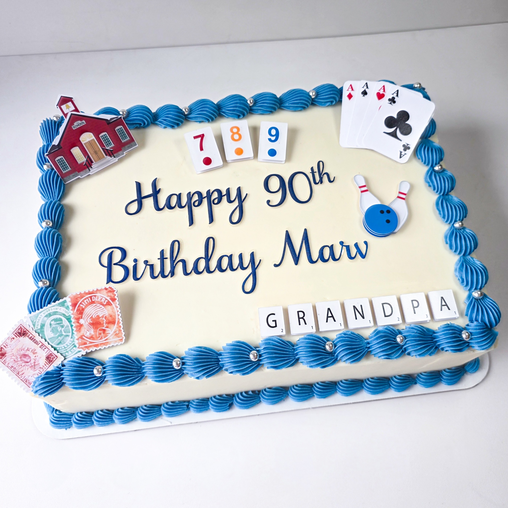 Ivory 90th birthday sheet cake with blue shell border, playing cards, bowling, and Scrabble Grandpa tiles