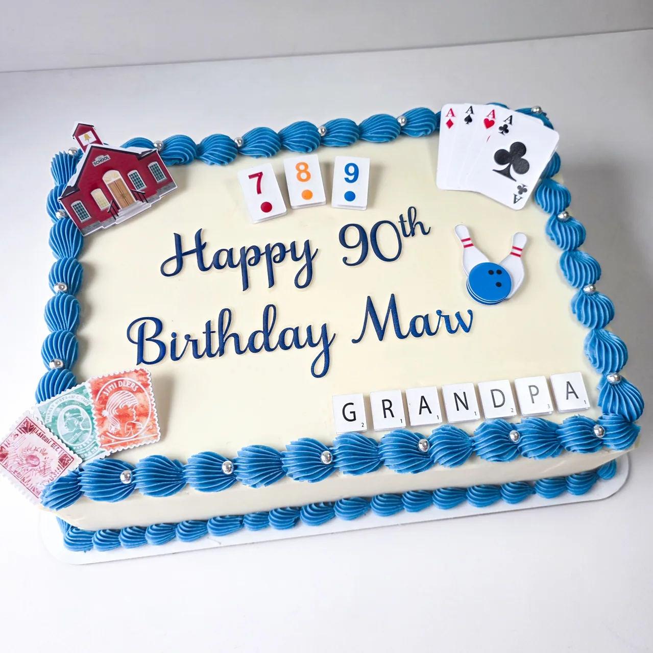 Ivory 90th birthday sheet cake with blue shell border, playing cards, bowling, and Scrabble Grandpa tiles