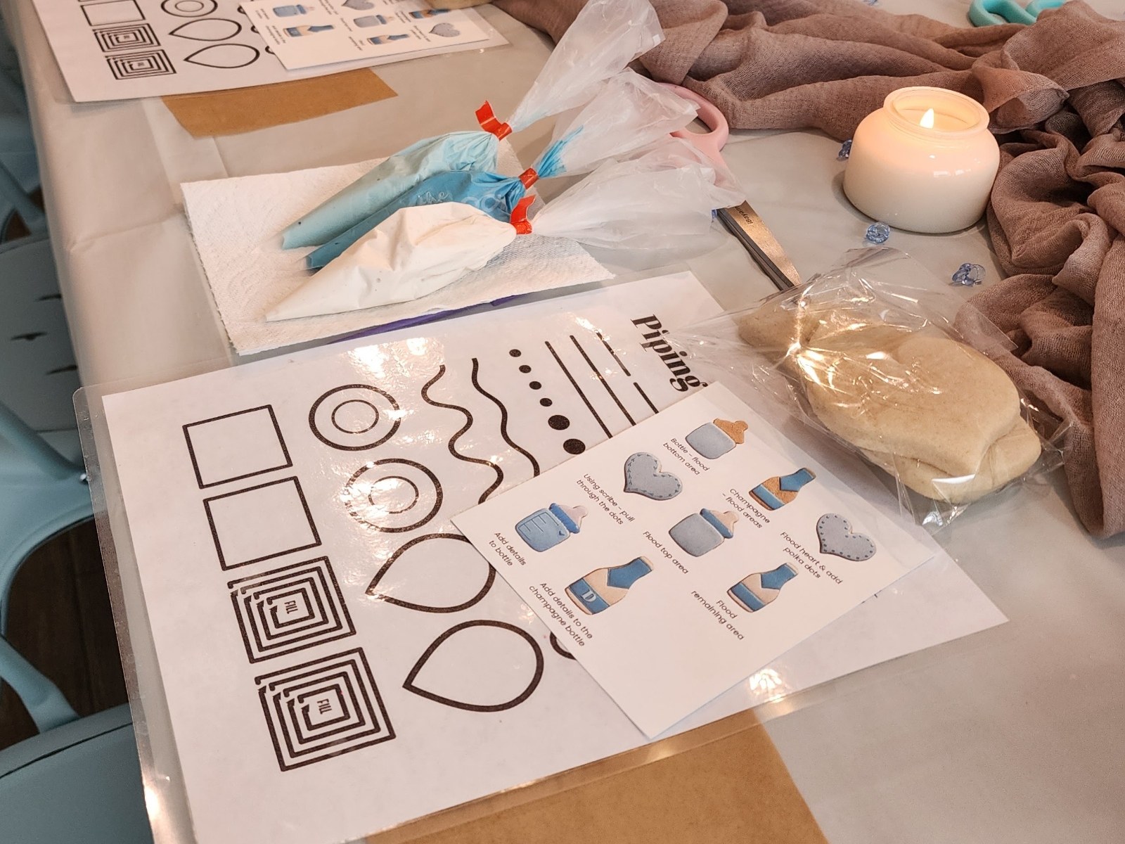 Styled cookie decorating class table with icing bags, cookies, and florals