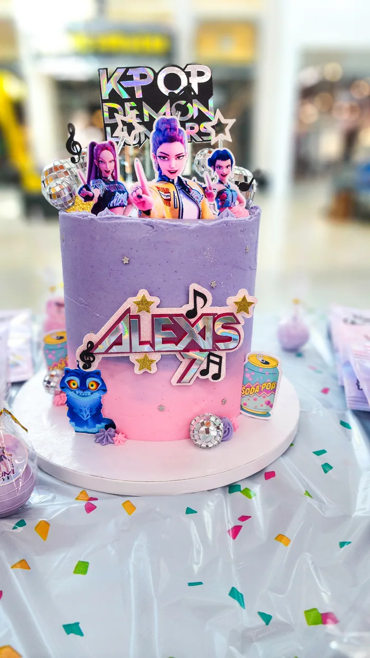 Purple and pink KPop Demon Hunters birthday cake with disco balls and character toppers