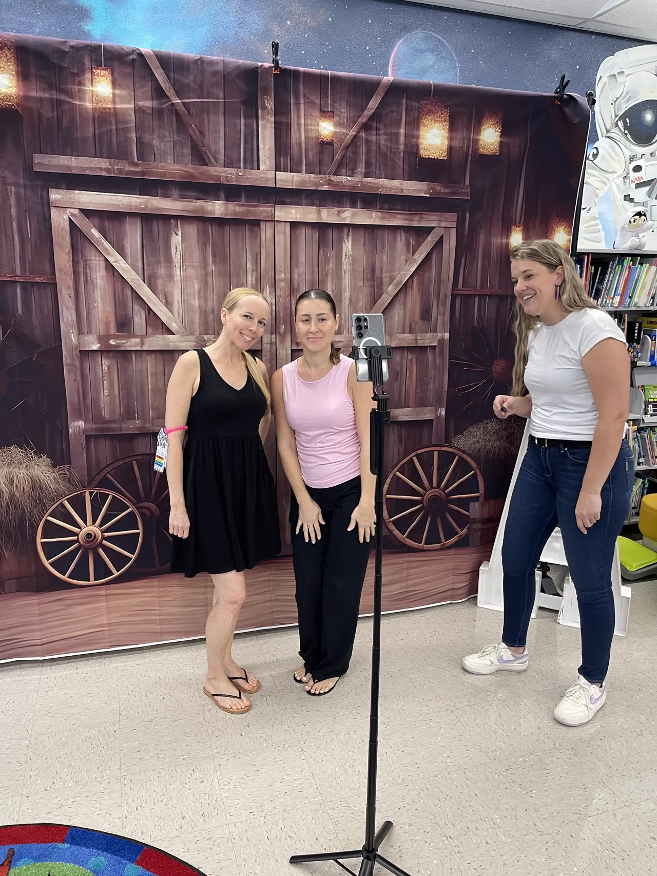 Two guests posing together in front of a rustic barn backdrop at the Ellie Mae's Bakery Cookie Photo Booth camera stand