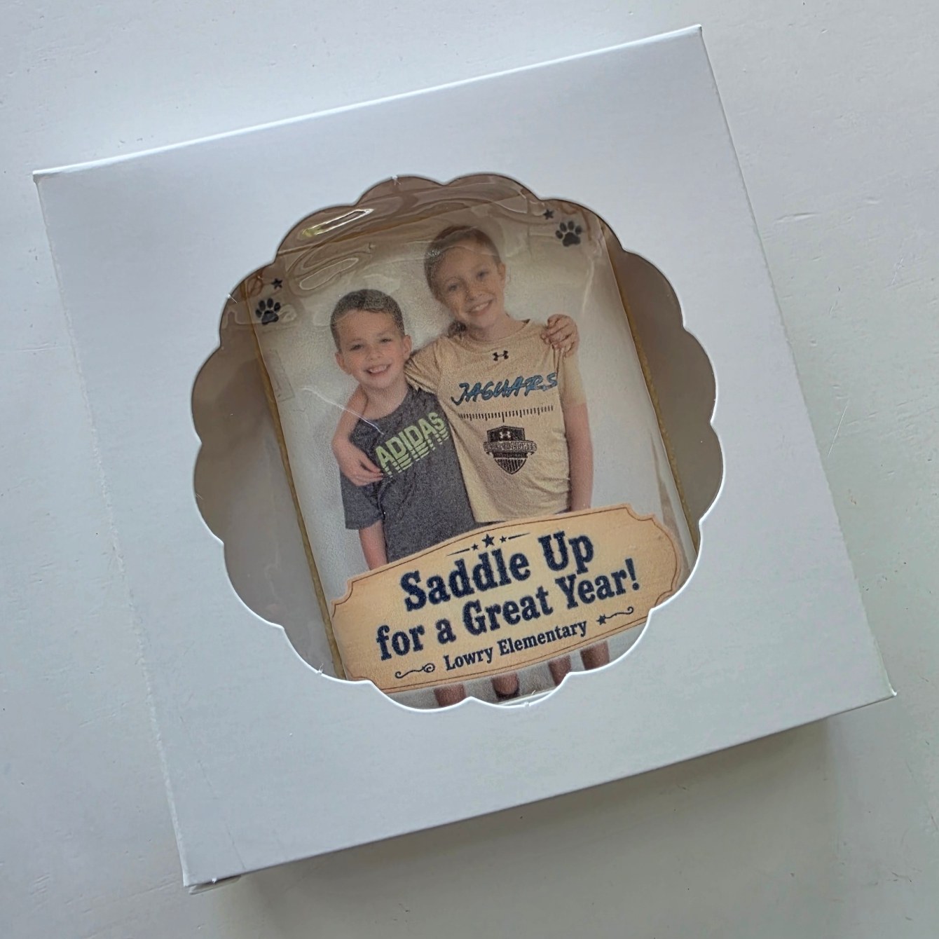 Angled view of a boxed photo cookie with a scalloped window