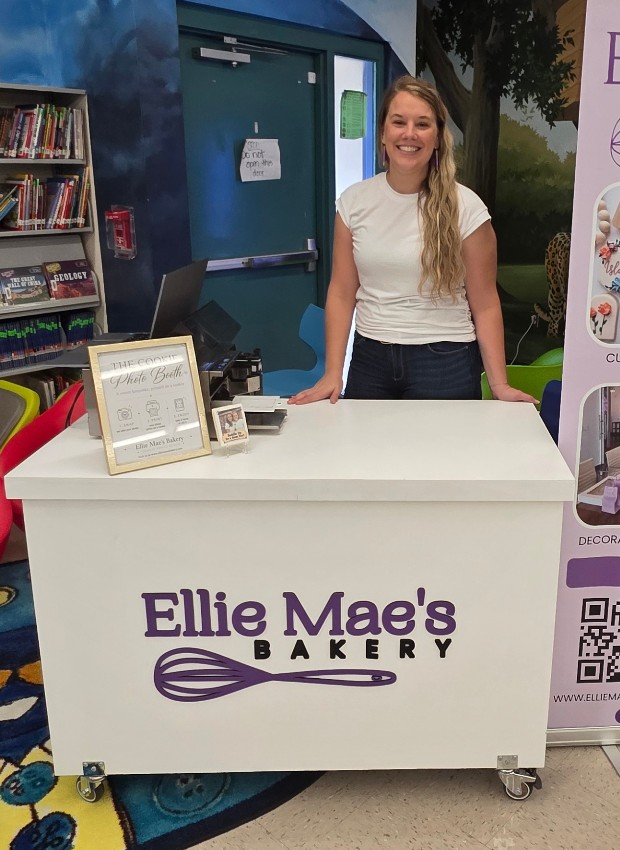 Ellie standing behind the white Ellie Mae's Bakery Cookie Photo Booth cart
