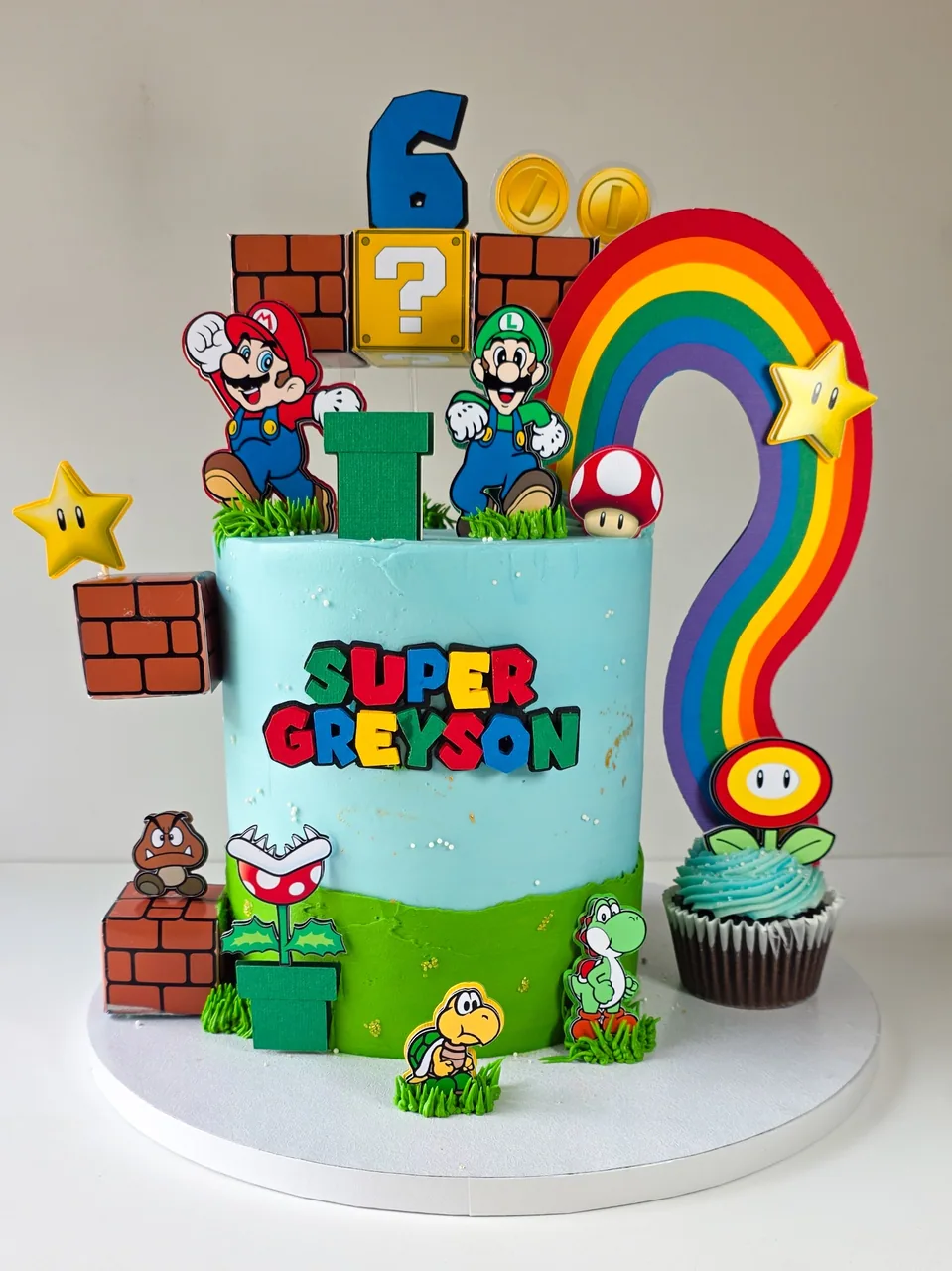 Super Mario themed birthday cake with blue and green buttercream, rainbow, and character toppers